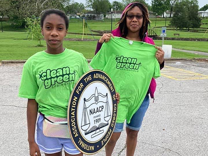 two african american women wearing clean green tee shirts and holding a NAACP sign