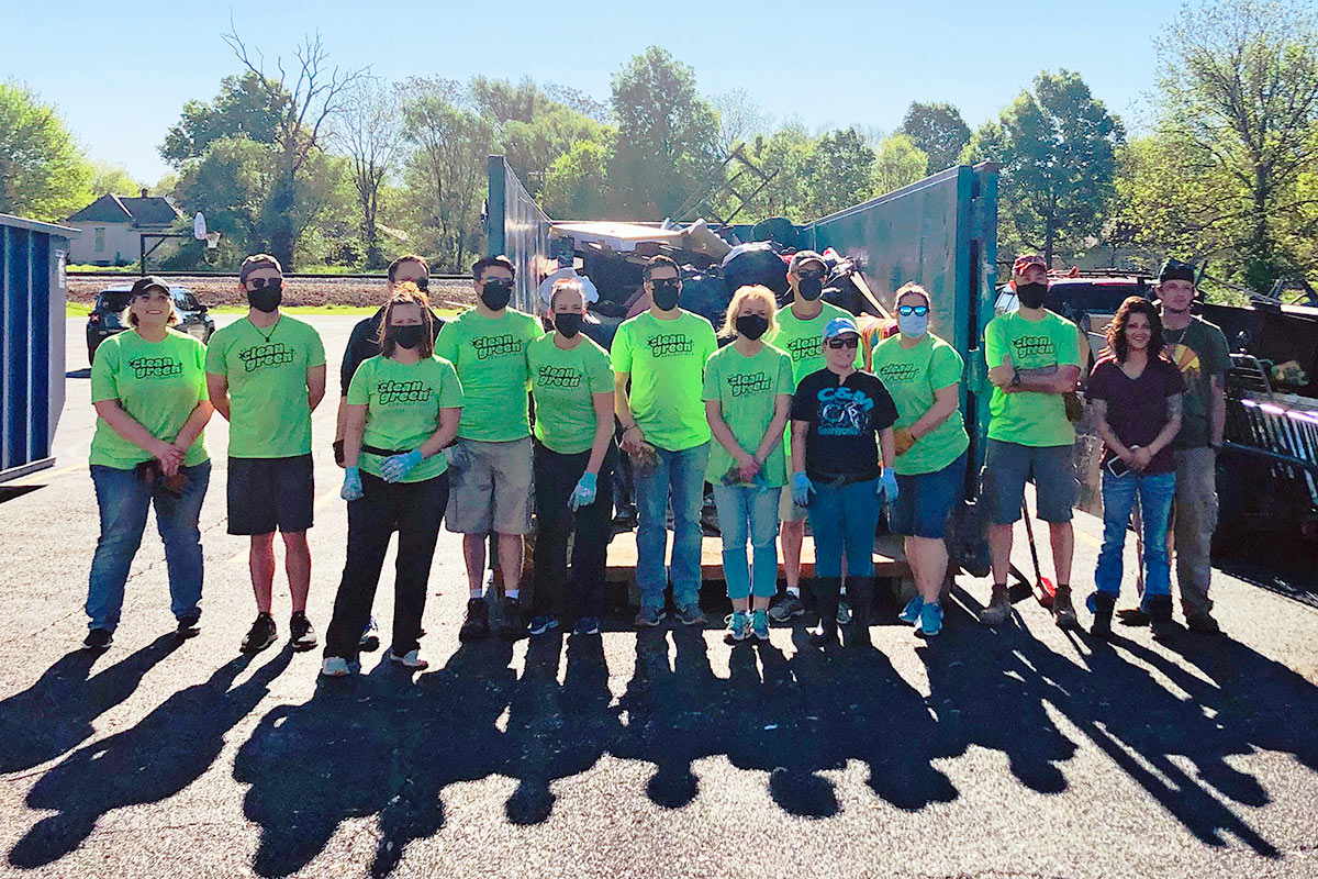 group of volunteers standing in front of a large dumpster
